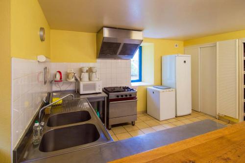 une cuisine avec un évier et un réfrigérateur dans l'établissement Grande maison conviviale à Saint-Côme-d'Olt avec jardin et cheminée, à Saint-Côme-dʼOlt