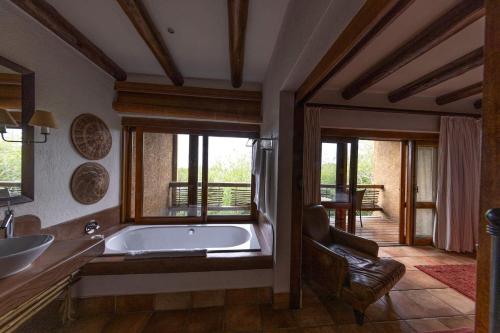 uma ampla casa de banho com uma banheira e uma cadeira. em Kapama River Lodge em Kapama Private Game Reserve
