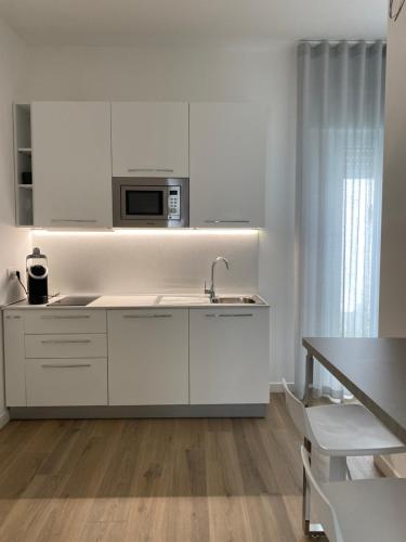 a white kitchen with a sink and a microwave at Dimore Capirro Charming Family House in Trani
