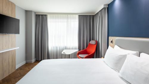 una camera d'albergo con letto e sedia rossa di Holiday Inn Express Amsterdam - Sloterdijk Station, an IHG Hotel ad Amsterdam