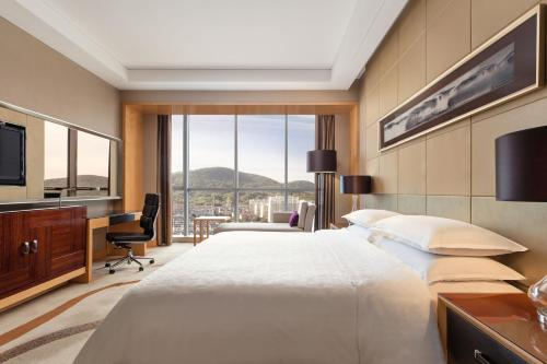 a hotel room with a large bed and a desk at Sheraton Zhenjiang Hotel in Zhenjiang
