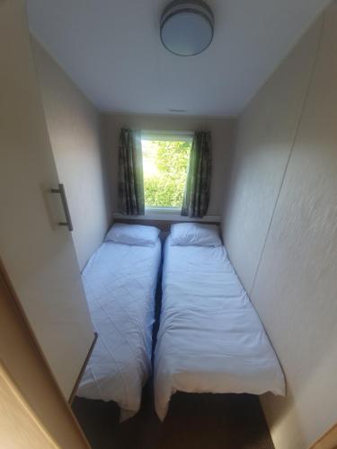 Duas camas num pequeno quarto com uma janela em Fantasy Island King Fisher 8Berth 401 em Ingoldmells