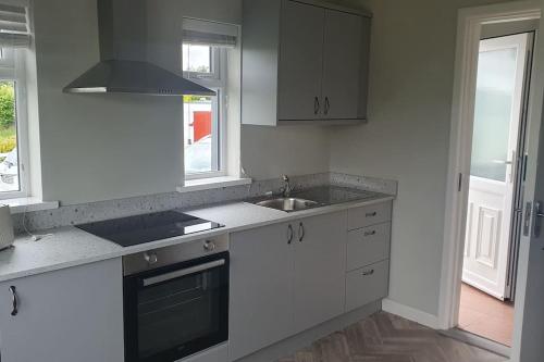 a kitchen with white cabinets and a sink and a window at 3 bedroom house close to lough sheelin in Cavan
