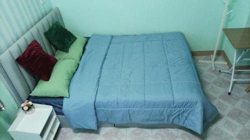 a bed in a bedroom with a blue comforter at Jatuporn A1 in Pathum Thani