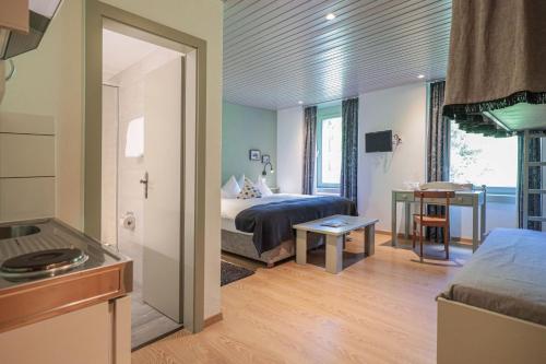 a room with a bed and a kitchen with a table at Hotel Seehof-Arosa in Arosa