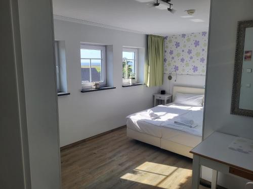 a bedroom with a white bed and two windows at Der Landhof Wildrose in Stolpe