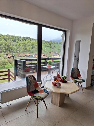 ein Wohnzimmer mit einem Tisch und Stühlen sowie einem großen Fenster in der Unterkunft Pensiunea Podul Simonului in Bran
