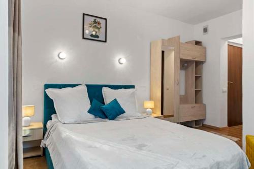 ein Schlafzimmer mit einem großen weißen Bett mit blauen Akzenten in der Unterkunft Pensiunea Podul Simonului in Bran