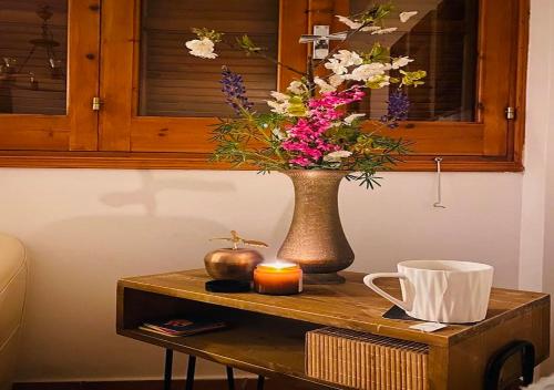 a vase of flowers on a table with a candle at Vavatsinia Panorama Cottage in Vavatsinia