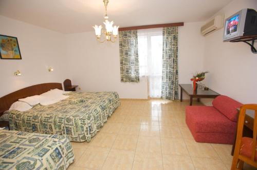 Habitación de hotel con 2 camas y sofá rojo en Family Hotel Orfei, en Nesebar