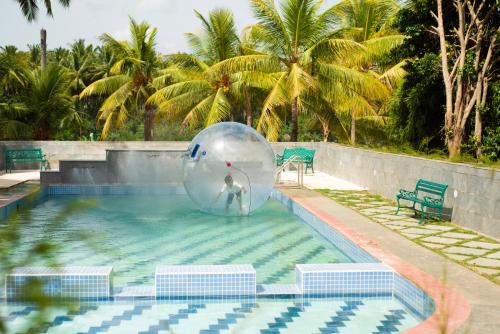 una persona en una pelota en el agua en una piscina en Ibex River Resort, Pollachi, en Coimbatore