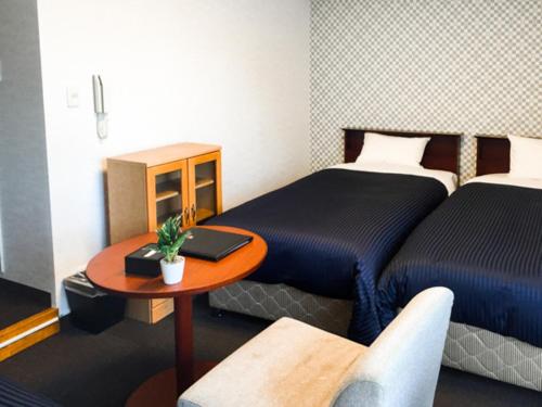 a room with two beds and a table with a laptop on it at HOTEL LiVEMAX BUDGET Fuchu in Fuchu