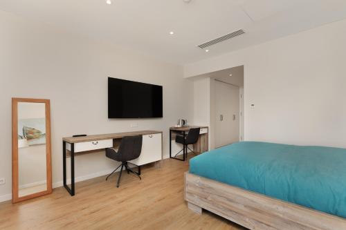 a bedroom with a bed and a desk and a television at Boulevard Hotel Batumi in Batumi