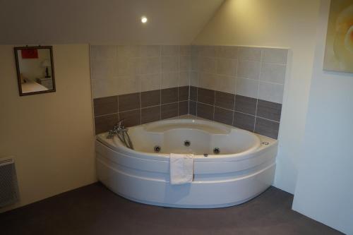 a large white tub in a bathroom with a tile wall at Logis Domaine des Chais in Thénac