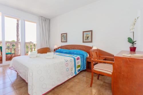 um quarto com uma cama, uma mesa e uma cadeira em Villa Lidia em Cala Galdana