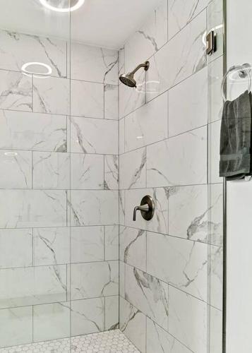 a bathroom with a shower with white marble tiles at Lake Home, Dock, Fire Pit, Hot Tub, Game Room, Etc in Winchester