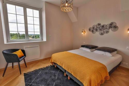 ein Schlafzimmer mit einem Bett und einem Stuhl und einem Fenster in der Unterkunft Domaine Grand Piquecaillou - L'appartement Saint Emilion in Saint-Maixant