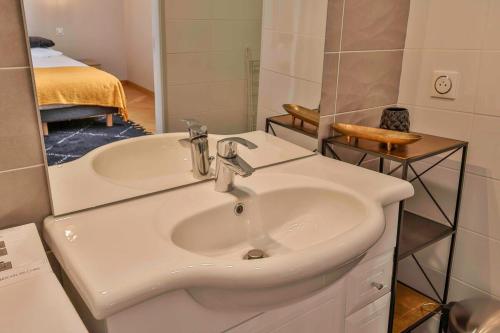 ein Badezimmer mit einem weißen Waschbecken und ein Schlafzimmer in der Unterkunft Domaine Grand Piquecaillou - L'appartement Saint Emilion in Saint-Maixant