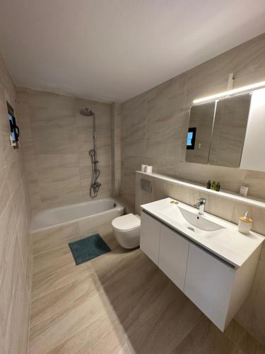 a bathroom with a sink and a toilet and a tub at Callisto Beach Hotel in Liapades