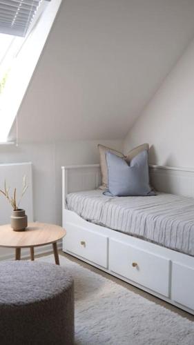 a white bedroom with a bed with a table at Lovely villa at the foot of the Funen Alps in Fåborg