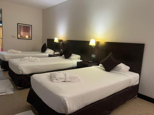 a hotel room with three beds with white sheets at Al Jazira Club Hotel in Abu Dhabi