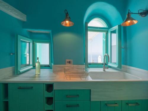 a blue kitchen with a sink and a window at Aegean Garden Apartment in Kardhianí