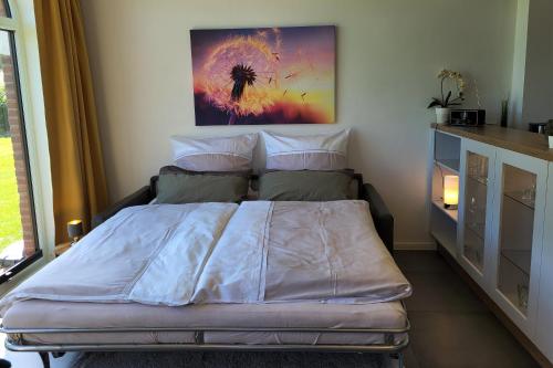 1 dormitorio con 1 cama con una pintura en la pared en FEWO Wiesenschlummerland Harriersand en Schwanewede