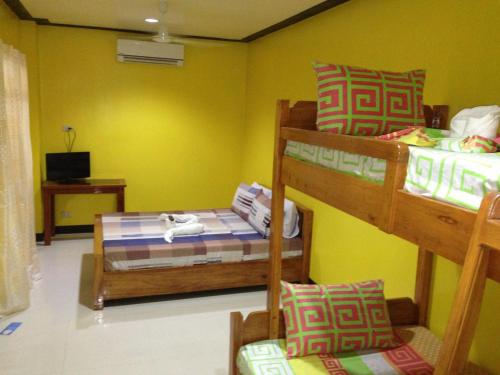 a room with three bunk beds and a tv at OYO 938 Citrine Travel Lodge in El Nido