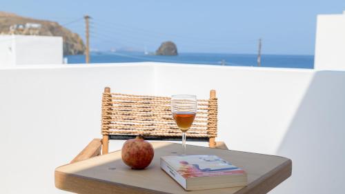 a glass of wine on a table with a book and an apple at Nove Milos Luxury by Estia in Pollonia