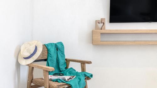 una mecedora de madera con un sombrero sentado frente a una TV en Nove Milos Luxury by Estia en Pollonia
