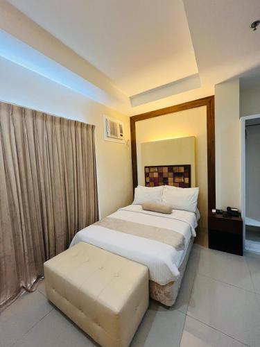 a bedroom with a large bed and a stool at Sierra Hotel in Dumaguete
