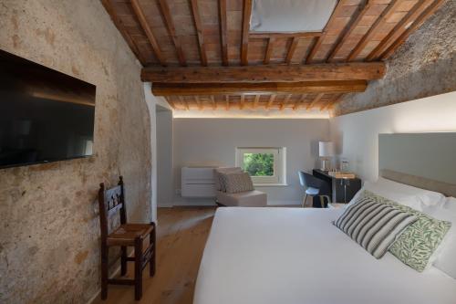 - une chambre avec un lit blanc et une télévision dans l'établissement Corte Massimago, à Mezzane di Sotto