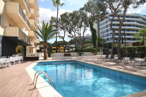 einen Pool mit Stühlen und ein Gebäude in der Unterkunft Cabot Tres Torres Apartamentos in Playa de Palma