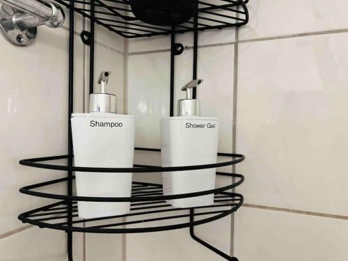 a black wire shelf with two soap dispensers in a bathroom at Nordsee Appartement in Hagen in Hagen