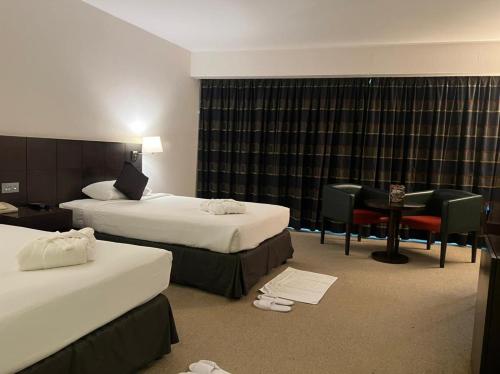 a hotel room with two beds and a desk at Al Jazira Club Hotel in Abu Dhabi