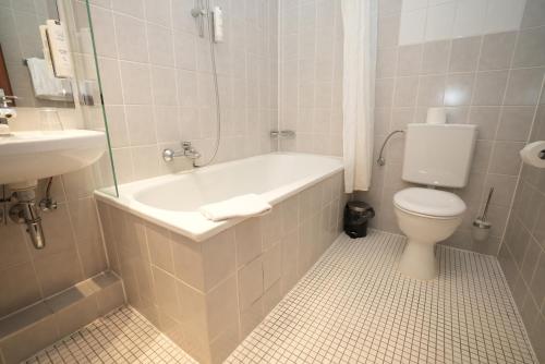 a bathroom with a tub and a toilet and a sink at Hotel Attaché an der Messe in Frankfurt/Main