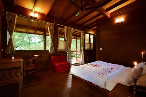 a bedroom with a white bed and a red chair at Stanmore Garden Bungalow in Vālpārai