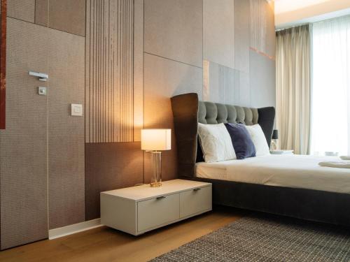 1 dormitorio con 1 cama y 1 mesa con lámpara en Luxury Living: Spectacular Views & Modern Elegance en Bucarest