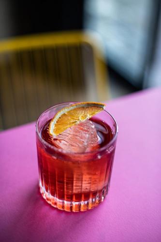 a drink with an orange slice on a pink table at Hotel Kitchen59 in Sofia