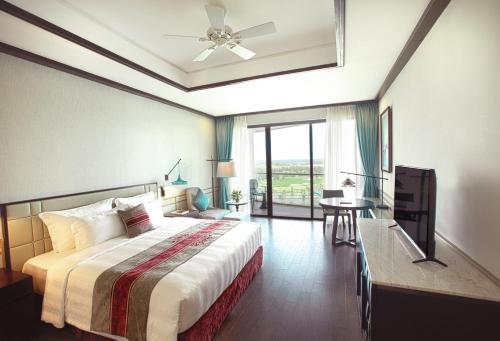 a bedroom with a bed and a desk and a window at Vinpearl Resort & Golf Nam Hoi An in Hoi An