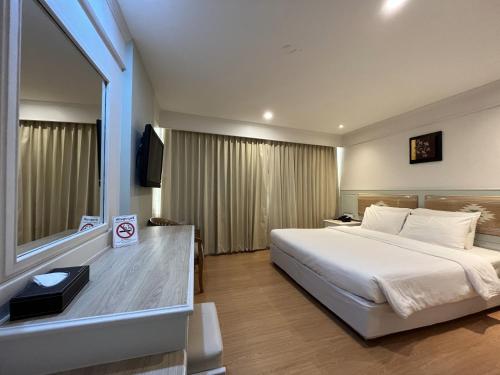 um quarto de hotel com uma cama grande e uma janela em Dhevaraj Hotel em Nan