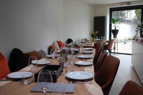 uma longa mesa de madeira com copos e pratos em Huis Nest Logies em Halle