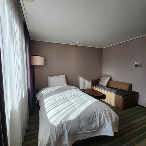 a hotel room with a bed and a chair at Avonhotel Gunsan in Gunsan
