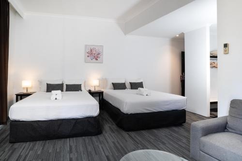 a hotel room with two beds and a couch at Joondalup City Hotel in Perth