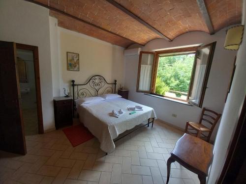 1 dormitorio con cama, ventana y silla en Podere S.Giulia - casale S.Giulia, en Riotorto