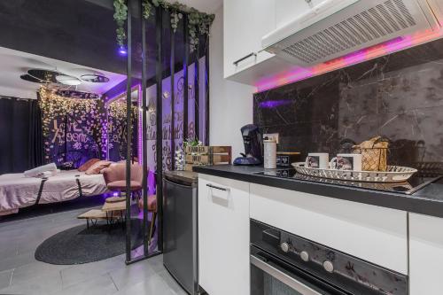 une chambre avec un lit et une cuisine avec un éclairage violet dans l'établissement LA ROMANTIQUE ROOM, à Montagnac