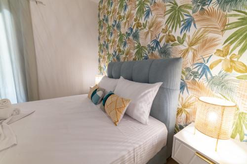 una camera da letto con un letto bianco e carta da parati tropicale di Villa Maria Tsovili a Párga