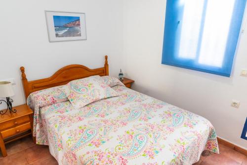 a bedroom with a bed with a comforter and a window at Casa Marinero - Patio Andaluz in Barbate