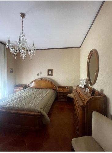 una camera con letto, specchio e lampadario a braccio di Casa Cecè a Canicattì