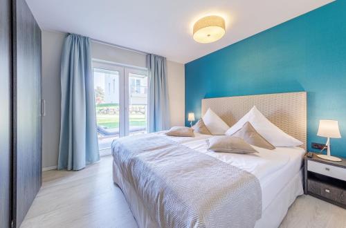 a bedroom with a large bed with a blue wall at Zwei Wasser - Strandhaus Alte Seefahrtschule in Wustrow